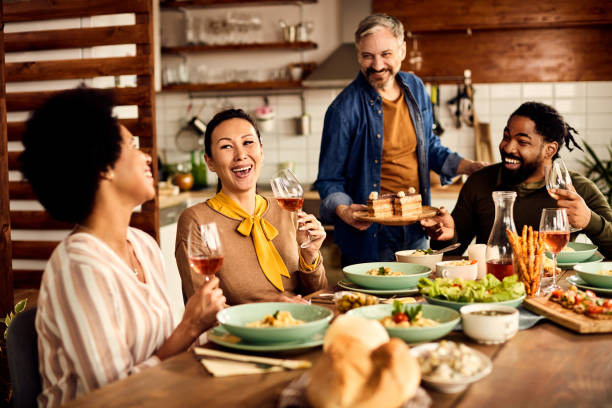 multi-ethic group of friends having fun during a meal at dining table. - eating people group of people home interior imagens e fotografias de stock