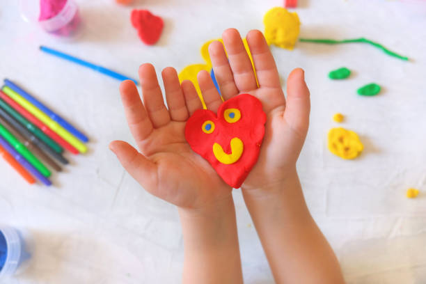 child playing with plasticine, colorful modeling clay and sculpting heart . home education game with clay. early development . - craft valentines day heart shape creativity imagens e fotografias de stock