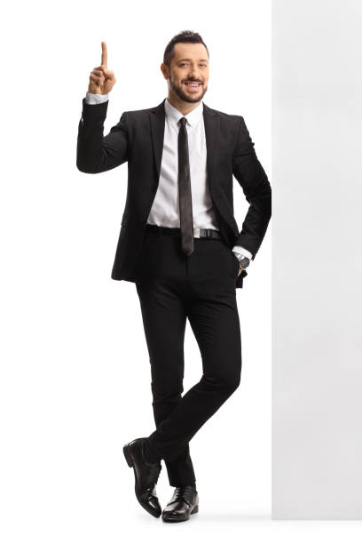 istock Professional man in a suit and tie leaning on a wall and pointing up 1313631036