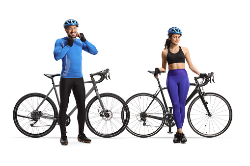 Young male and female cyclists leaning on their bikes isolated on white background
