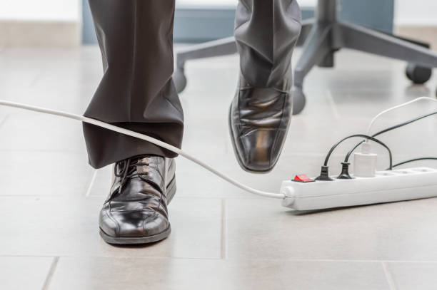 accident in the office with the cable Close up of a businessman legs stumbling with an electrical cord at office unsafe workplace stock pictures, royalty-free photos & images