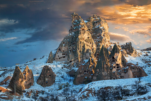 Volcanic rock formations in the town of Uchisar in the snow at the sunset in Cappadocia, Turkey