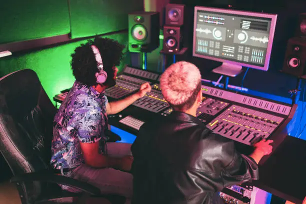 Photo of Musician and sound engineer mixing new album inside boutique recording studio - Technology and music industry concept - Main focus on man head