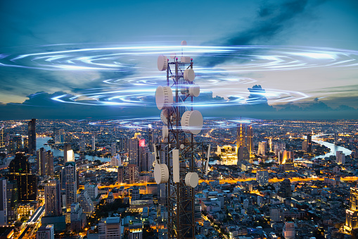 Telecommunication tower with 5G cellular network antenna wave on night city background