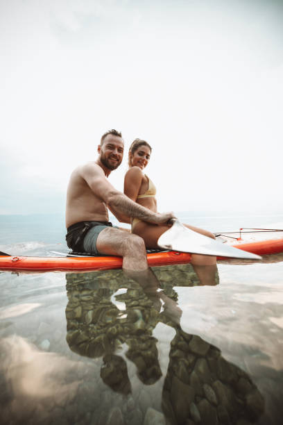 istock Smiling Couple Relaxing With Paddleboard On Lake During Vacation 1313637293