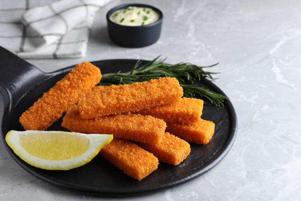 istock Fresh breaded fish fingers and lemon served on light grey table 1313638321