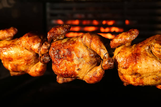 grillowanie całych kurcząt w maszynie do rotisserie, zbliżenie - rotisserie chicken roasted barbecue zdjęcia i obrazy z banku zdjęć