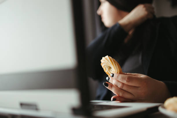 istock Woman multitasking eating sweets at her workplace 1313641555