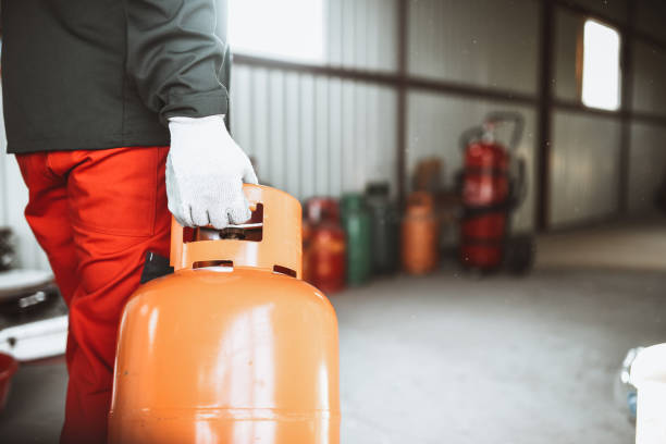 trabajador masculino llevando cilindro de gas a trastero en tienda de gas licuado - liquid propane gas fotografías e imágenes de stock