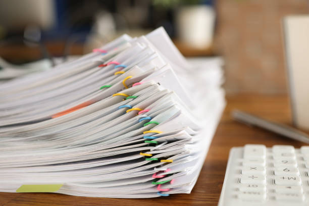 una gran cantidad de documentos fijados con clips de papel multicolores acostados en el primer plano de la mesa - paper clip clip paper office fotografías e imágenes de stock