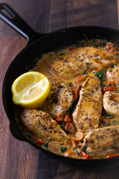 istock Creamy Tuscan Chicken in a cast iron skillet with fresh lemon wedge. 1313642949