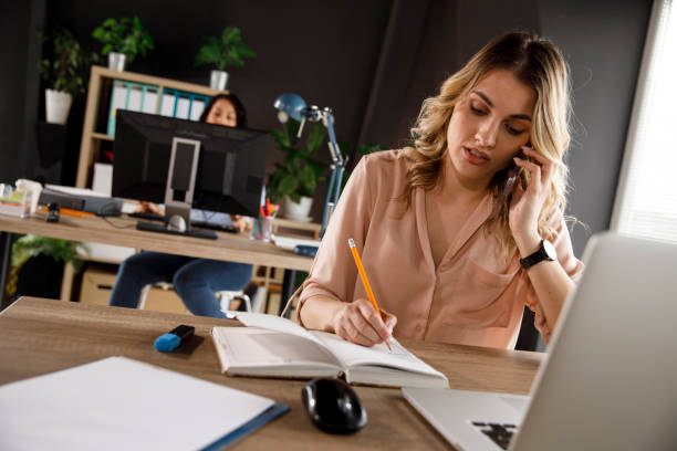 istock Serious young woman writing in her notebook during a conference call 1313643139