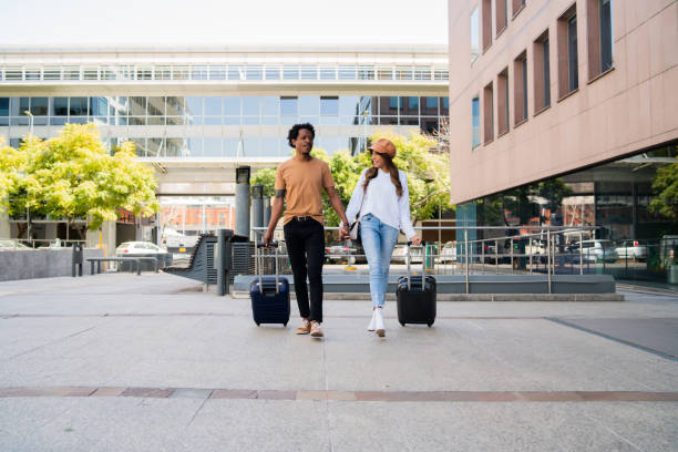 istock Tourist couple carrying suitcase while walking outdoors. 1313643241