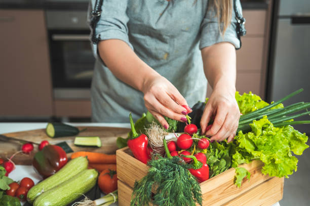 istock Woman unpacking fresh vegetables from wooden crate 1313643249