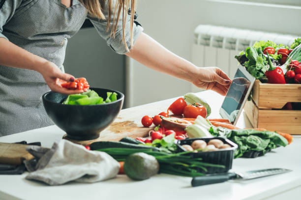 istock Unrecognizable woman reading recipe on digital tablet while cooking healthy lunch in modern kitchen 1313643263