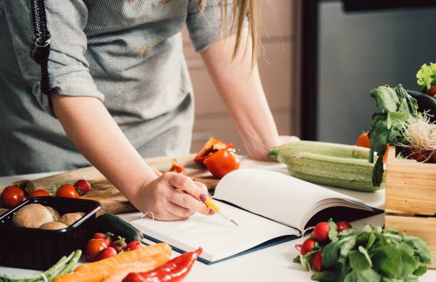 tanınmayan kadın yemek kitabında tarif arıyor - yemek kitapları stok fotoğraflar ve resimler