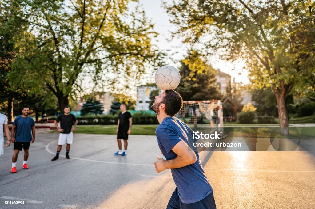 Man Juggling Soccer Ball With Head Man is juggling soccer ball with his head of urban soccer field. Soccer Stock Photo