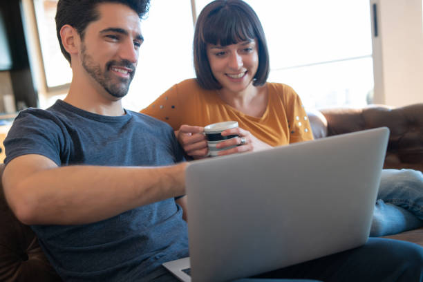 istock Couple using laptop while sitting on couch at home. 1313644121