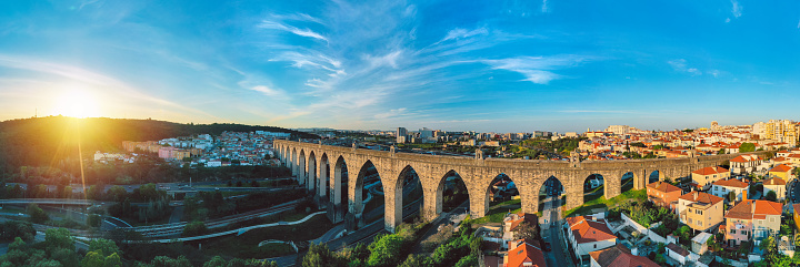 Historic aqueduct in Lisbon city. Aerial panoramic view of The Aguas Livres Aqueduct at sunset. Aqueduto das Aguas Livres or Aqueduct of the Free Waters in Portugal. High quality photo