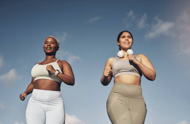 projectile de deux jeunes femmes dehors pour une course ensemble - brassière de sport photos et images de collection