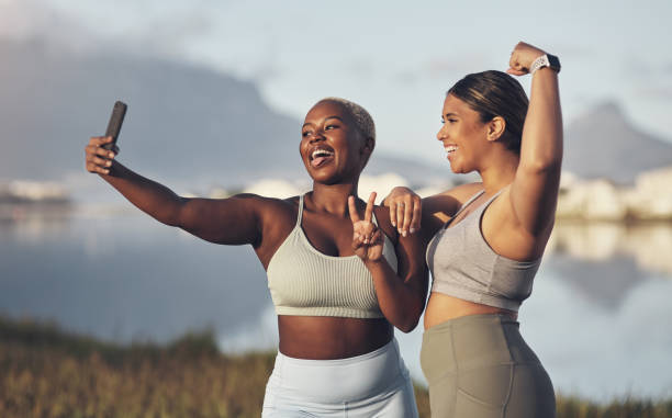 Shot of two women taking a selfie while out for a run
together We in on the bestie fitness challenge! hourglass photos stock pictures, royalty-free photos & images
