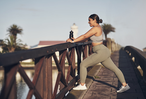 Shot of a young woman stretching on a footbridge