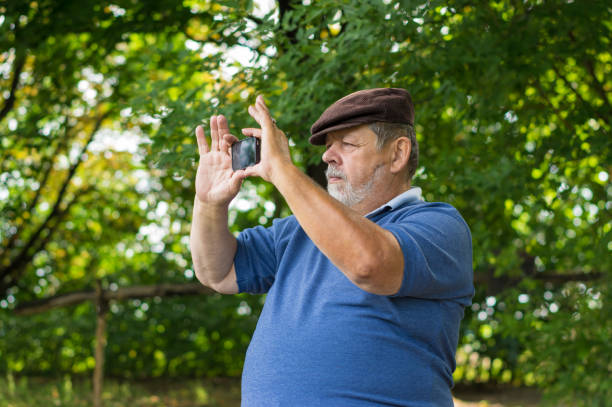 istock Caucasian bearded senior man using cellular phone outdoor making photos with internal camera 1313649375