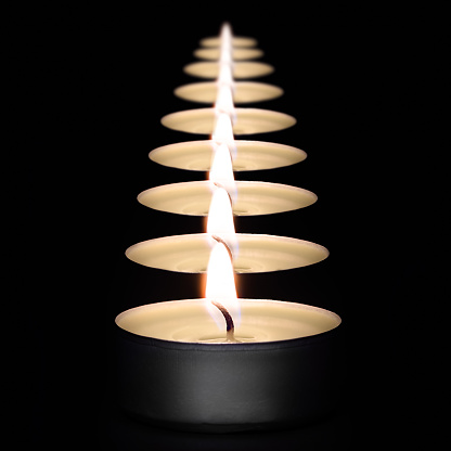 A row of burning candles on a dark background with a flare in the foreground. Layout, mockup.
