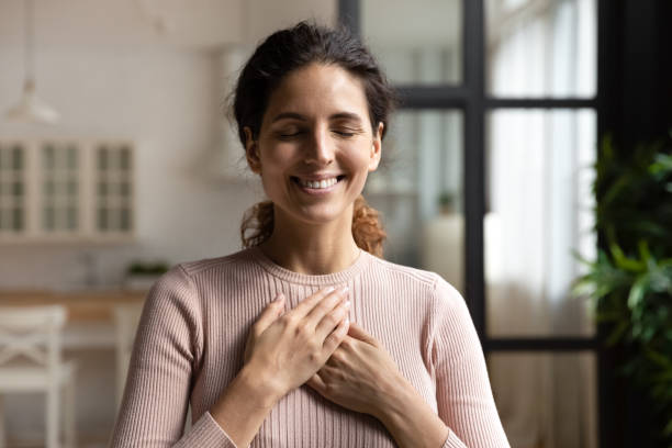 Peaceful hispanic female with closed eyes keep hands to heart Thank you my God. Happy peaceful millennial hispanic lady stand alone with closed eyes keep hands close to heart hope pray in mind. Emotional young woman express deep gratitude impressed by good deed mindfullness stock pictures, royalty-free photos & images