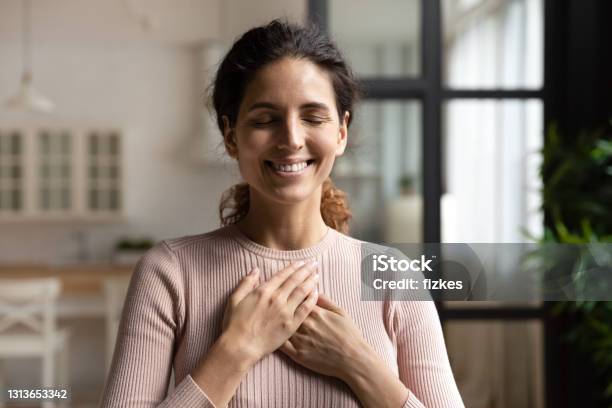 Peaceful Hispanic Female With Closed Eyes Keep Hands To Heart Stock Photo - Download Image Now
