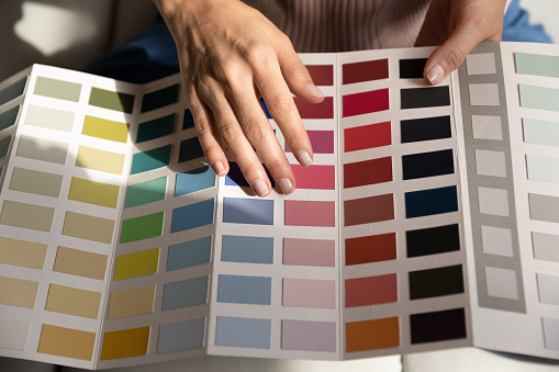 Selective focus on a palette with color swatches of watercolor paints of various spectrums, in the hands of a saleswoman demonstrating it to customer shopping in a stationery store. Painting and art