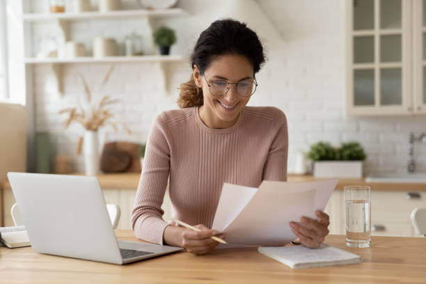 glückliche millennial hispanic dame bewertung gedruckte papier dokumente finanzberichte - home finances debt tax finance stock-fotos und bilder