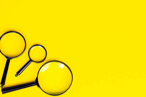 istock Black magnifying glass on light yellow background with copy space 1313653722