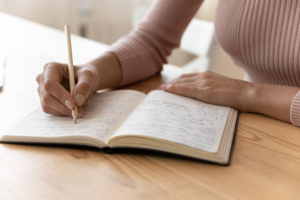 istock Young woman hand hold pencil take notes to paper daybook 1313653769