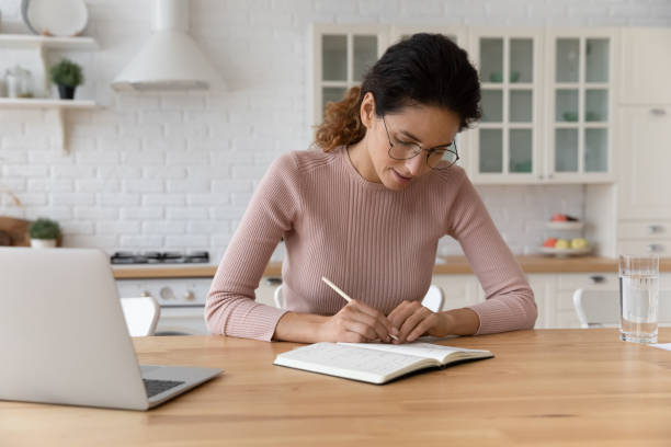 istock Concentrated millennial latin woman work with paper notebook make records 1313653788