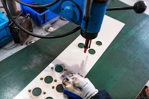 Professional young industrial factory man employee working with machine parts putting, checking and testing industrial equipments cables in large Electric electronics wire and cable manufacturing plant factory warehouse.