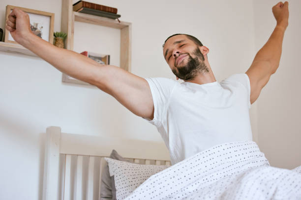 istock Shot of a young man waking up and stretching while in his bed 1313656621