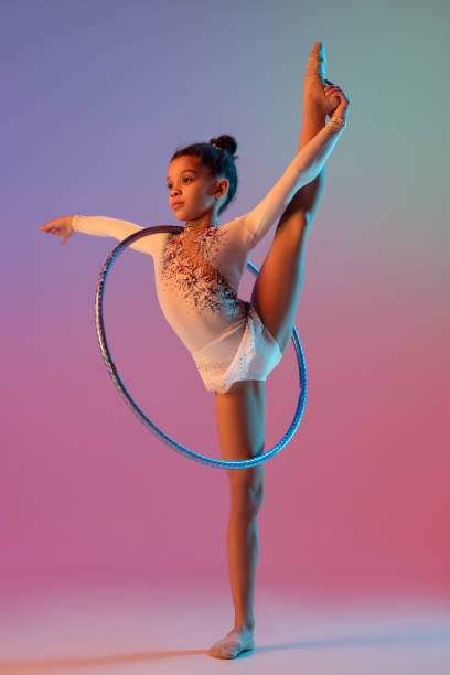 istock African-american rhythmic gymnast, pretty girl practicing on gradient studio background in neon light 1313656815