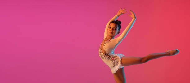istock African-american rhythmic gymnast, pretty girl practicing on gradient studio background in neon light 1313656835