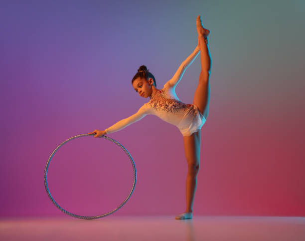 istock African-american rhythmic gymnast, pretty girl practicing on gradient studio background in neon light 1313656868
