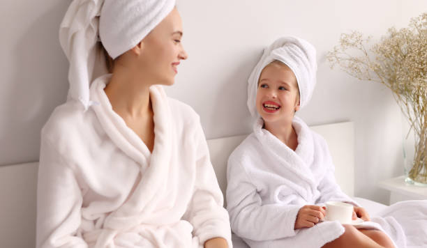istock Mother and daughter enjoying hot drink on bed 1313656874