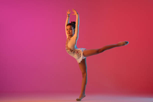 istock African-american rhythmic gymnast, pretty girl practicing on gradient studio background in neon light 1313656892