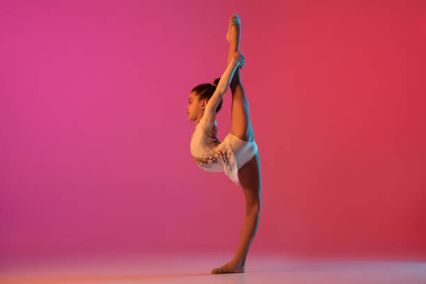 istock African-american rhythmic gymnast, pretty girl practicing on gradient studio background in neon light 1313656910