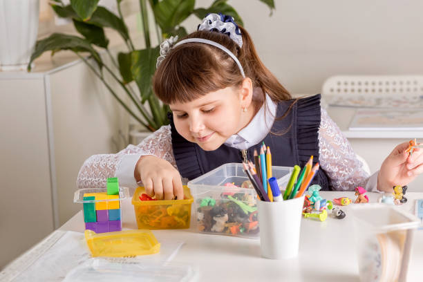 istock A girl pupil disassembles a box with small toys (motor skills development). 1313657511