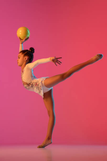 istock African-american rhythmic gymnast, pretty girl practicing on gradient studio background in neon light 1313657555