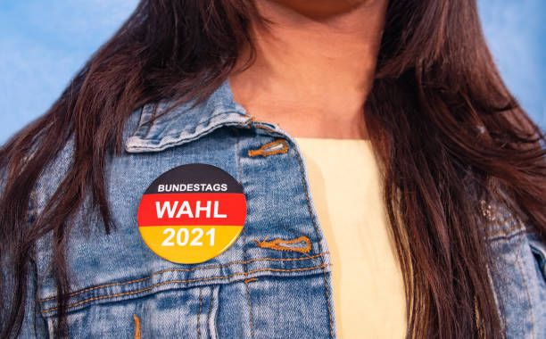 jovem de cabelo castanho e um botão eleitoral para a eleição federal alemã em sua jaqueta jeans , com a inscrição: "bundestagswahl 2021" (eleição federal 2021). - german culture people women germany - fotografias e filmes do acervo