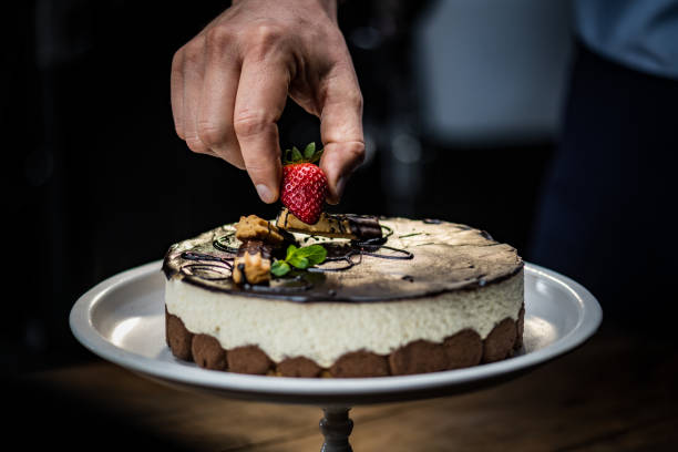 istock Man's hand placing strawberry on mousse cake 1313659242