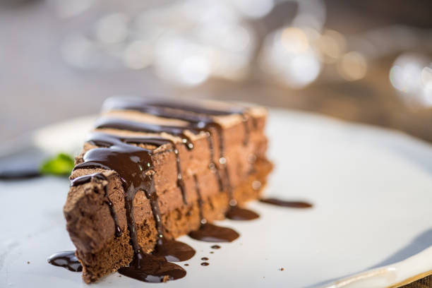 Close-up of slice of chocolate cake with brown fudge sauce served on plate.