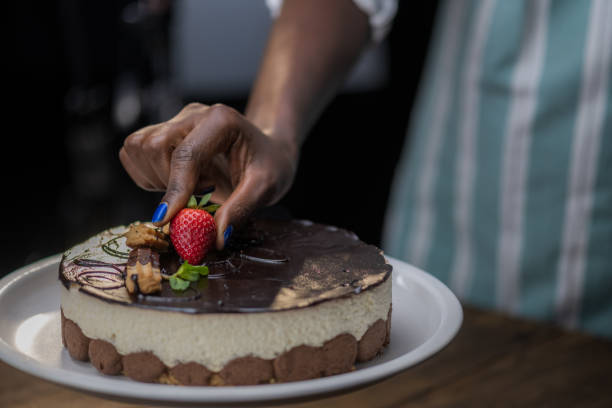 istock Woman's hand placing strawberry on mousse cake 1313659327
