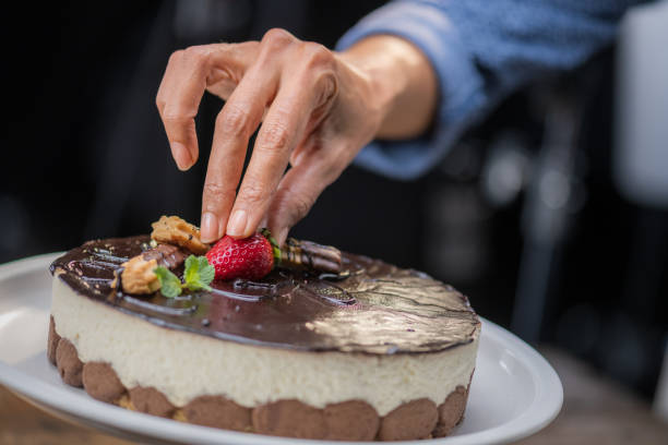 istock Woman's hand placing strawberry on mousse cake 1313659359